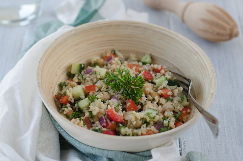 Light bulgur salad with cucumber, red pepper, chickpeas, and onion, seasoned with olive oil, garlic, lemon juice, and herbs is a fresh summer meal.